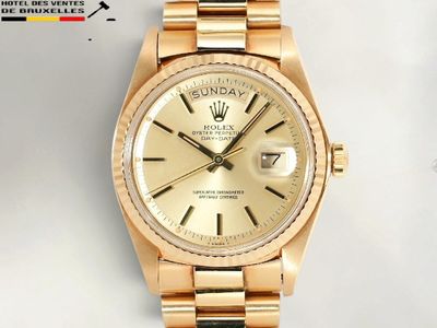 une photo d'une montre Rolex dorée posée sur une surface blanche