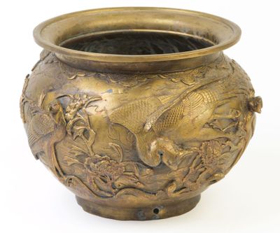 un vase en bronze orné d'un oiseau sur fond blanc