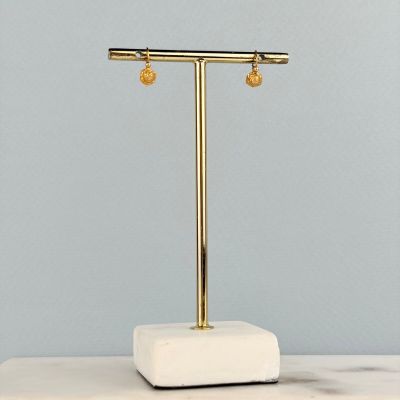 une paire de boucles d'oreilles en or posée sur un socle en marbre