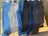 Plusieurs paires de jeans sont empilées sur une palette dans un entrepôt