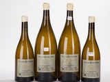 quatre bouteilles de vin sont alignées sur une surface blanche
