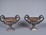 pair of antique cast iron urns on pedestals on grey background