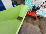 a green dumpster sitting in front of a graffiti covered wall
