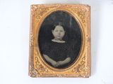 an old photo of a young girl in a black dress in a gold frame