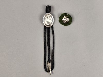 two pieces of silver and black cord with a coin on it