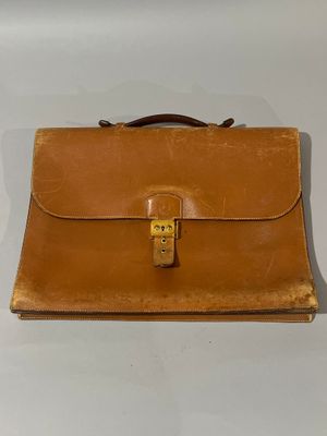 une vieille mallette en cuir marron posée sur une table blanche