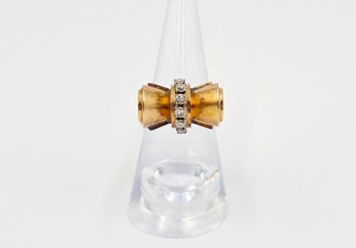 bague en forme de nœud en cristal et or, montée sur un cône en acrylique transparent