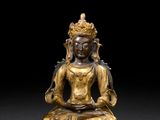 bronze figure of a seated buddha on a pedestal