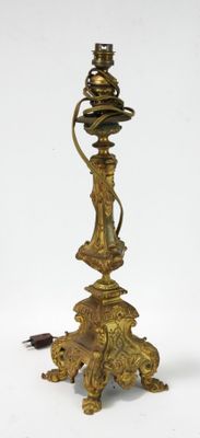une lampe ancienne en laiton surmontée d'une tête de lion