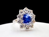 a close up of a blue sapphire and diamond ring on a white plate