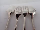 three forks and two spoons on a white table