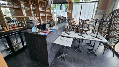 tables and chairs in a room with a bar and a window