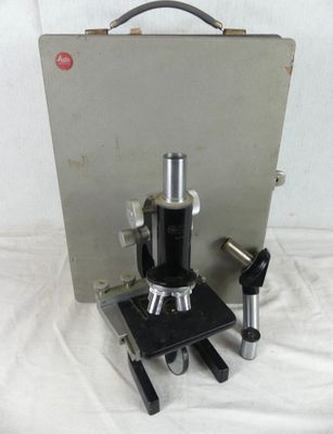 an old microscope with a metal case on a white surface