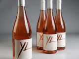 four bottles of pink wine are lined up on a table