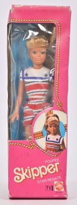 une poupée dans une boîte rose sur laquelle figure l'image d'une petite fille en tenue de marin