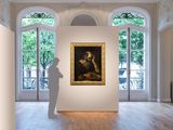 a man standing in a room with a painting on the wall