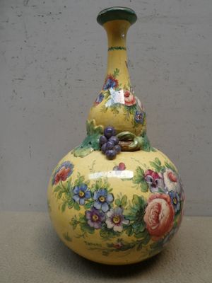 un vase jaune orné de fleurs peintes, posé sur une table