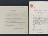 an old letter with a leaf on it sitting next to a piece of paper