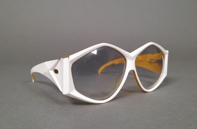pair of white sunglasses on a gray surface with a gray background