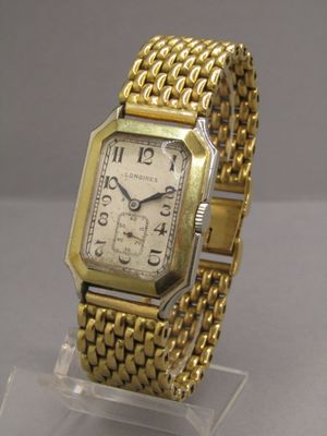 une montre en or posée sur un socle transparent, sur une table