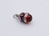 a close up of a silver and red stone pendant on a white surface