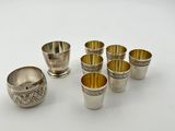 a group of silver cups and bowls on a white surface