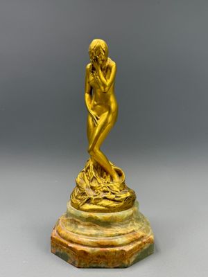une statue en or représentant une femme assise sur un socle en marbre