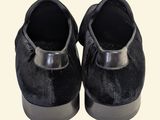 pair of black velvet slippers with silver trims on a white background
