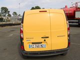 a yellow van parked in a parking lot with a red truck in the background