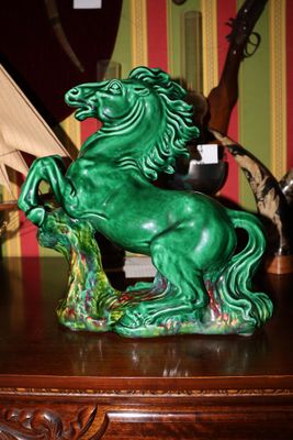 une statue de cheval verte posée sur une table, avec un bateau en arrière-plan