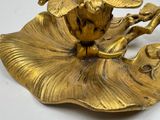 a gold figurine of a bird sitting on a leaf