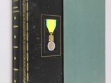 an old book with a medal on it sitting on a wall