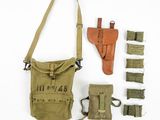 le contenu d'un sac militaire est disposé sur une surface blanche