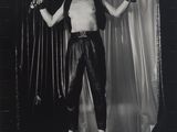 black and white photograph of a man in leather pants holding a pair of scissors