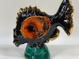 an orange and black fish figurine sitting on top of a green base