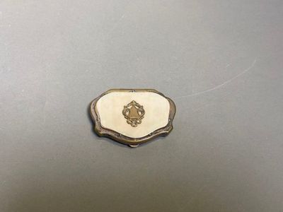 un plat ancien en argent orné d'un emblème blanc et doré