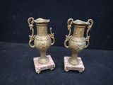 pair of antique brass urns on marble bases on a black background