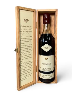 une vieille bouteille de vin dans un coffret en bois, accompagnée d'une lettre manuscrite