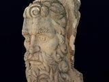 statue d'un homme barbu à tête de bouc sur fond noir