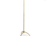 a gold floor lamp with a white shade on top of it