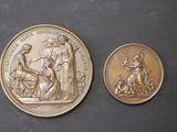 two gold medallions depicting the birth of jesus and the birth of mary