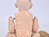 a small doll sitting on the ground with a nut in it ' s hand