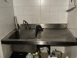 un lavabo dans un coin de la salle de bains, avec de nombreux produits d'entretien