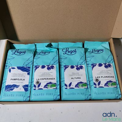 four bags of coffee sit in a cardboard box on a table