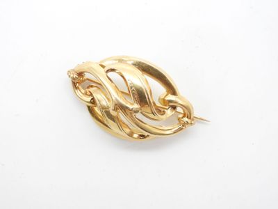 gros plan d'une broche en or sur une surface blanche