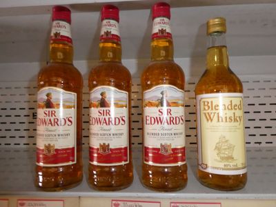 Plusieurs bouteilles d'alcool sont posées sur une étagère dans un magasin