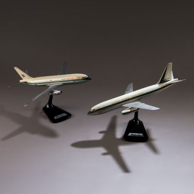 Trois maquettes d'avions sont posées sur un socle, sur une surface grise.