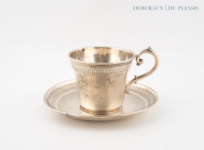 une tasse et une soucoupe anciennes en argent, posées sur une soucoupe