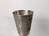 an old silver cup sitting on top of a glass table