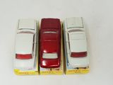 four toy cars are lined up in a row on a white surface